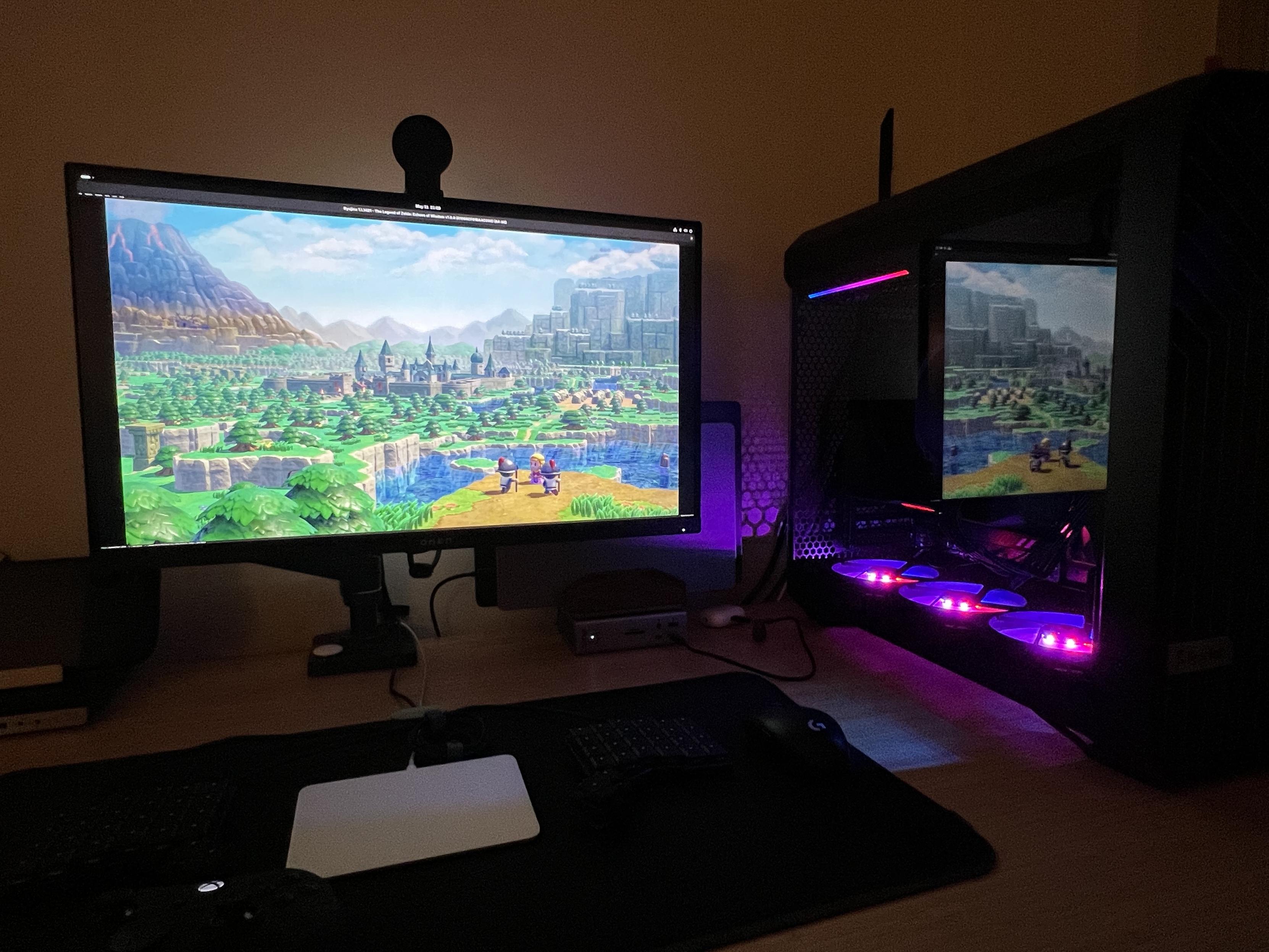 A desk mounted monitor sitting next to a large pc case that is glowing from the rgb fans inside. The monitor is showing some game play from Legend of Zelda - Echos of Winsdom. 🤫 Don’t tell Nintendo.