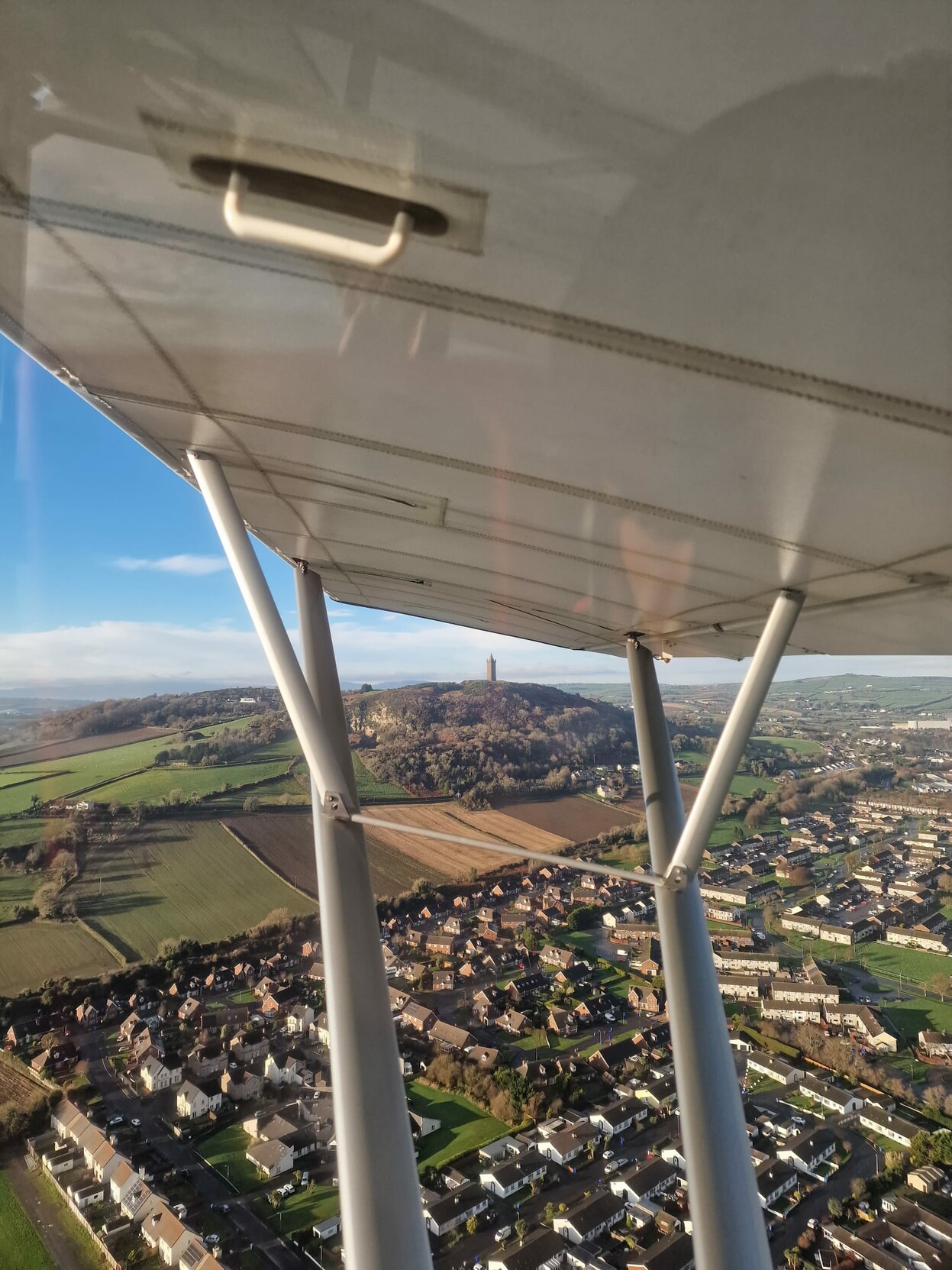 Scrabo Tower framed by wing struts on a light airplane 